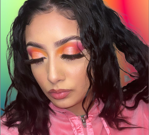 Vibrant sunset glam featuring bold orange and pink tones, soft matte skin, and fluttery lashes.